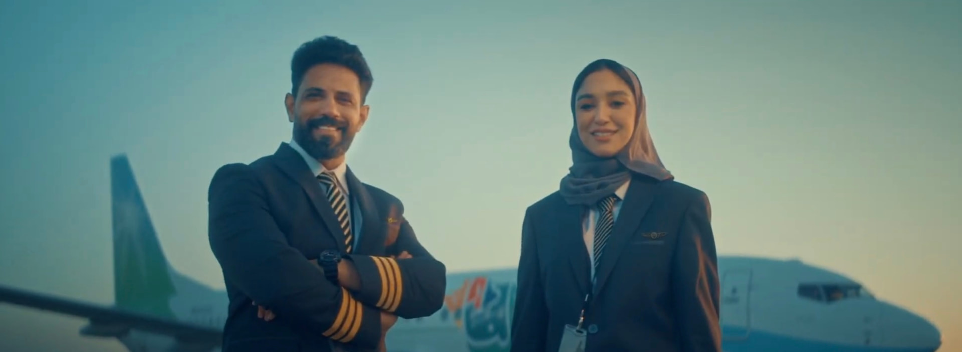 Two pilots standing in front of a Mukamalah airplane